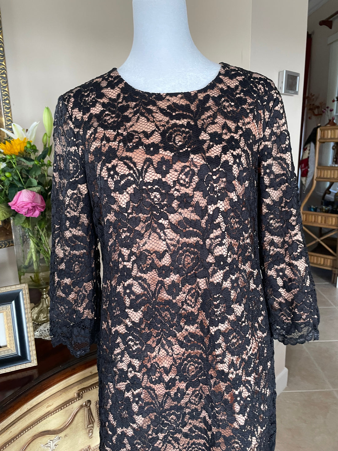 Black lace dress on a mannequin in a room with decor elements.